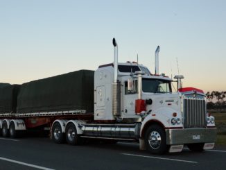 White flatbed truck driving at sunrise