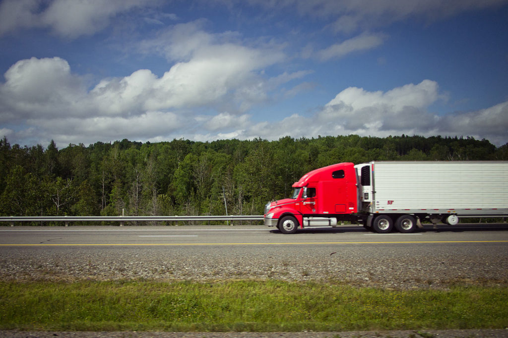 Truck driving on a straight path Red truck driving on a straight highway