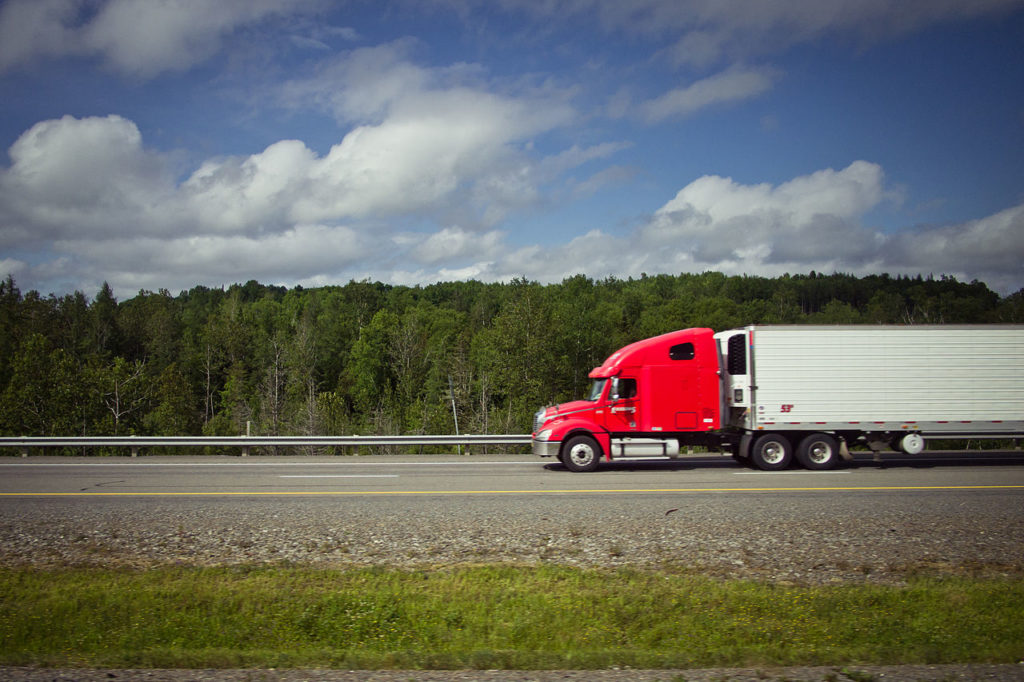 Red truck driving on a straight highway