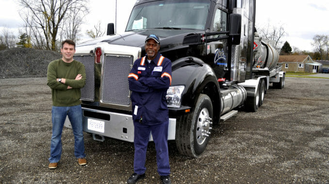 Two men stand in front of a big rig