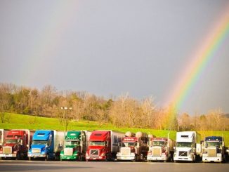 A line of trucks with a rainbow on the horizon