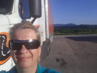 Truck driver and her truck take a photo