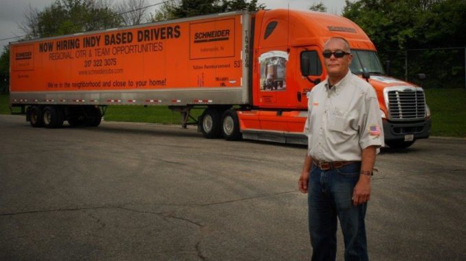 Driver stands next to his tractor-trailer