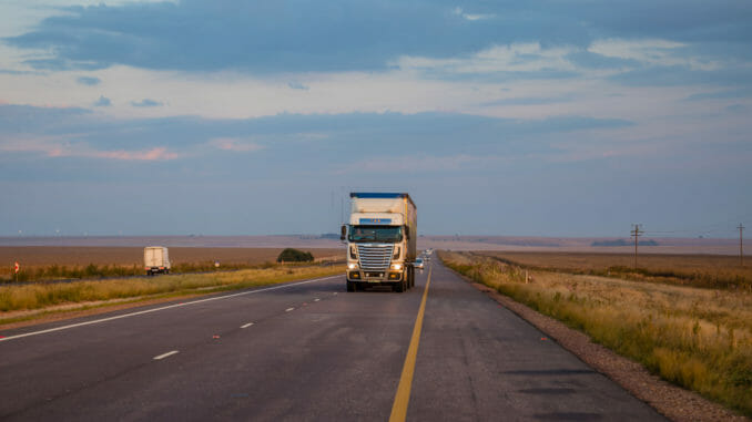 Truck driving on highway between fields i