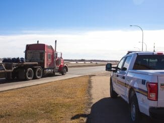 A police vehicle and a red truck driving past