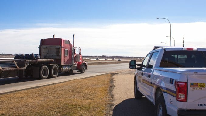A police vehicle and a red truck driving past