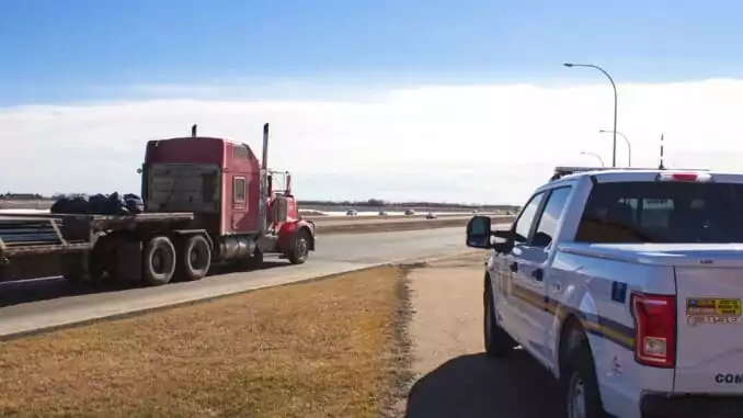 Police watches a truck pass by A police vehicle and a red truck driving past