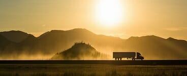 Truck driving silhouette on the highway at sunset